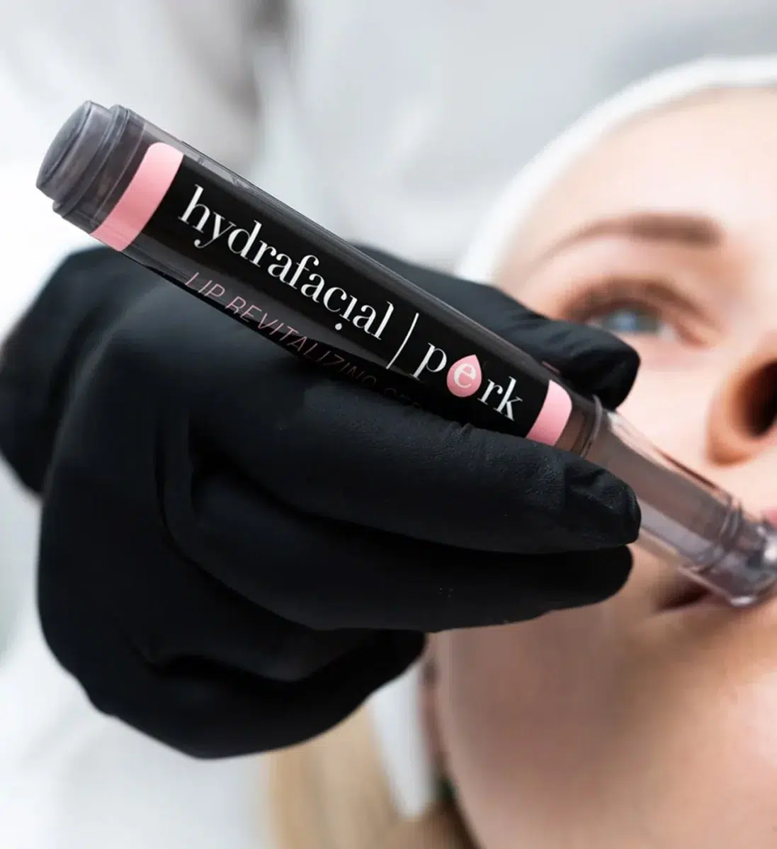 Козметолог държи спринцовка с продукт Hydrafacial Perk Lip
