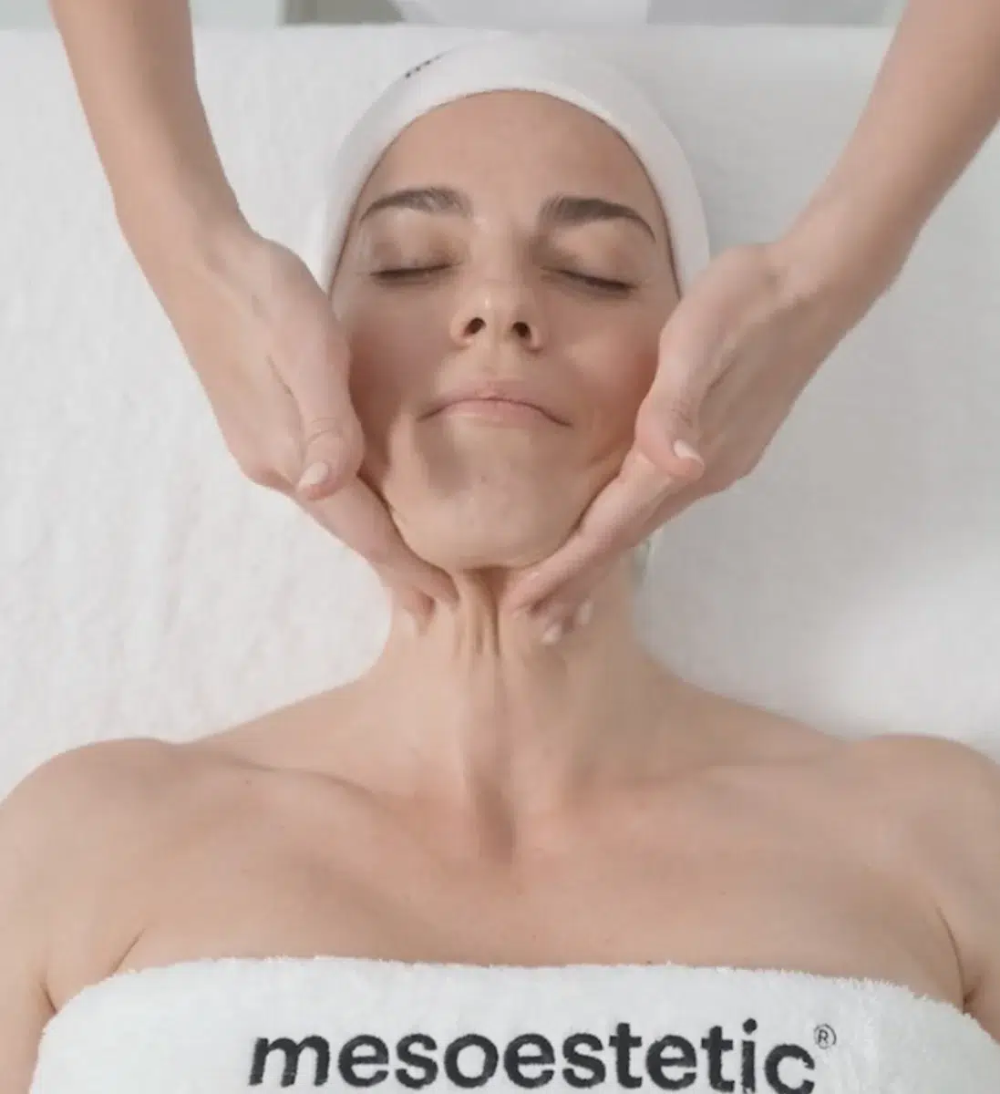 Козметолог масажира лицето на жена по време на процедура на mesoestetic